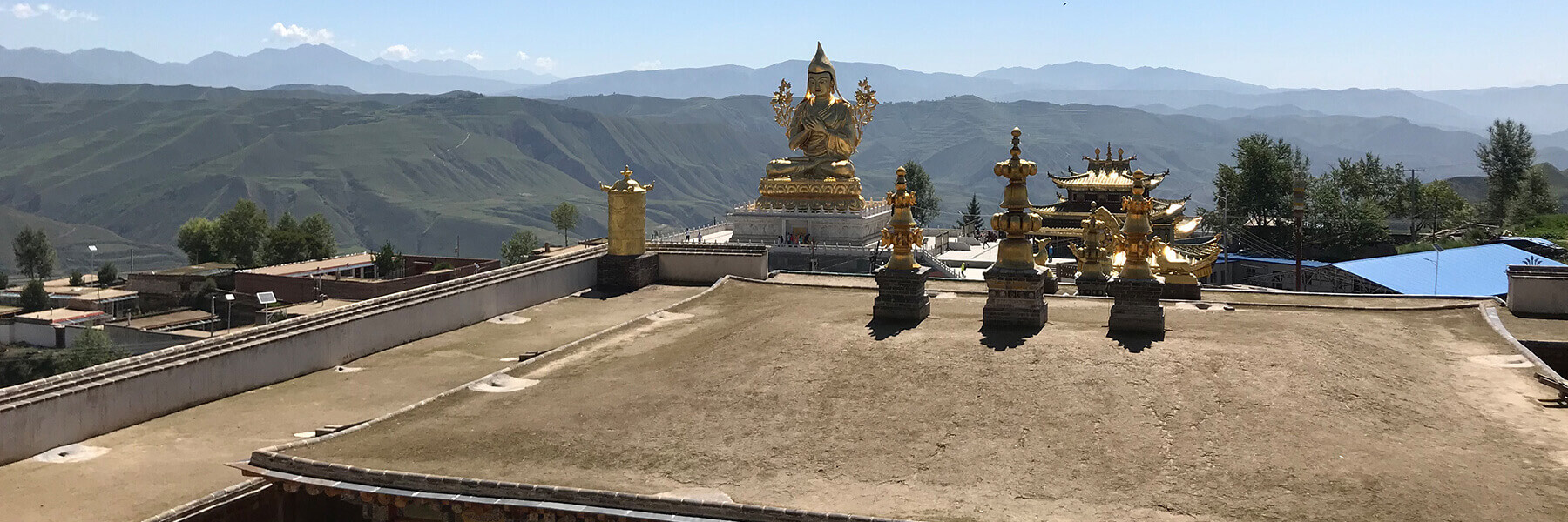 Gold Statue on top of a shrine with mountains in the distance